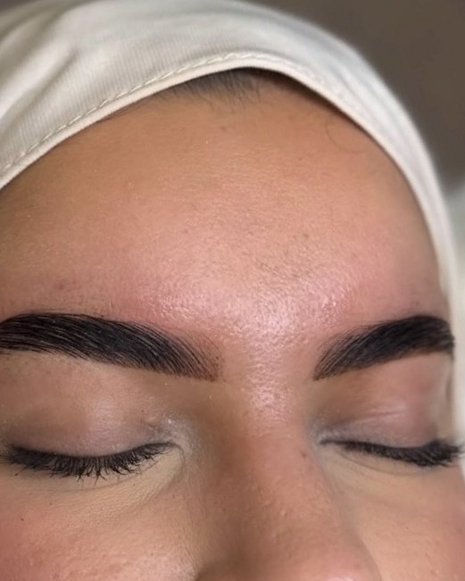 Halal brows: geblondeerde, strak in model gebrachte wenkbrauwen bij een klant met hoofddoek, ogen dicht